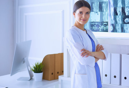 Portrait of young female doctor in white coat standing in hospital with her hands crossedの写真素材