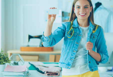 Beautiful young designer with business card in officeの写真素材