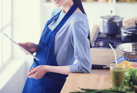 Young woman using a tablet computer to cook in her kitchenの写真素材