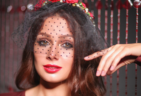 Romantic retro styled woman in black veil with red flowers in hair.の写真素材