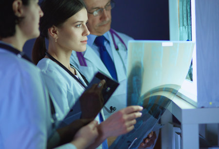 Group of doctors examining x-rays in a clinic, thinking of a diagnosisの写真素材
