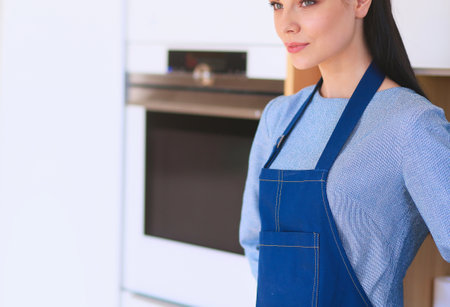 Portrait of young woman standing with arms crossed against kitchen backgroundの写真素材