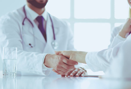 Doctor shaking hands with a male patient in the officeの写真素材