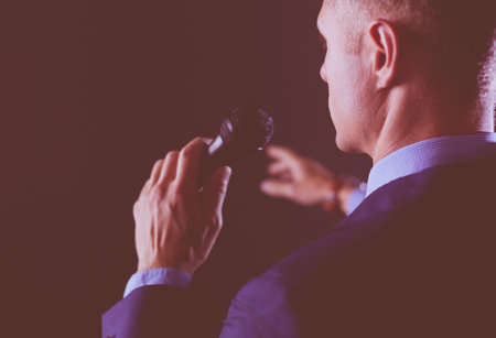 Portrait of a businessman standing with a microphone and looking ahead, speak at the conferenceの写真素材