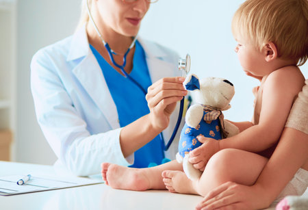 Female doctor is listening kid with a stethoscope in clinicの写真素材
