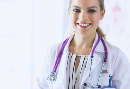 Smiling female doctor with a medical stethoscope in uniform standingの写真素材