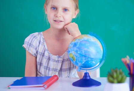 Girl studying at the desk, sitting on the desk.の写真素材