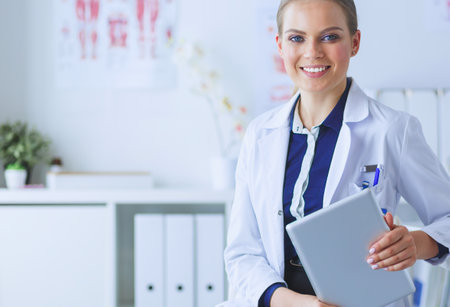 Portrait of woman doctor at hospital corridor, holding tablet computer, looking at camera, smilingの写真素材