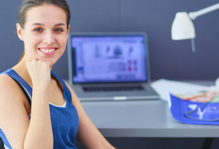 Young woman sitting at the desk with instruments, plan and laptop.の写真素材