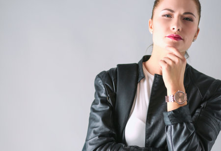 portrait of beautiful young brunette woman in stylish black jacket on gray.の写真素材