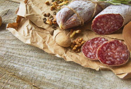 Italian salami wih sea salt, rosemary, garlic and nuts on paper. Rustic style. Close up.の写真素材