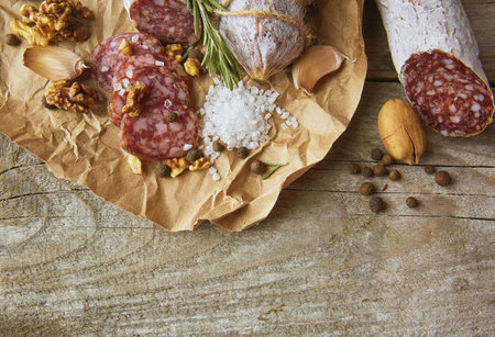 Italian salami wih sea salt, rosemary, garlic and nuts on paper. Rustic style. Top view.の写真素材