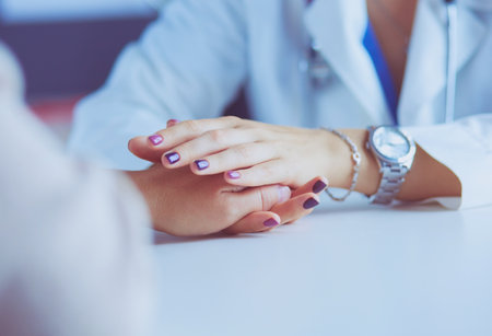Woman doctor helping senior holding hand in hospitalの写真素材