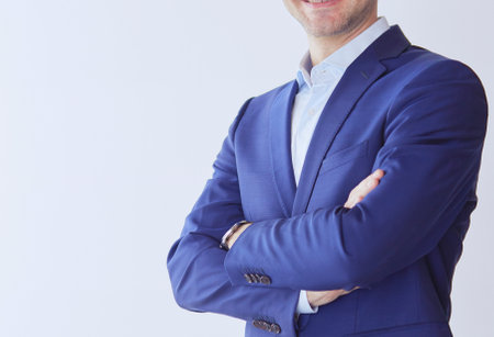 Handsome businessman standing with arms crossed on grey backgroundの写真素材