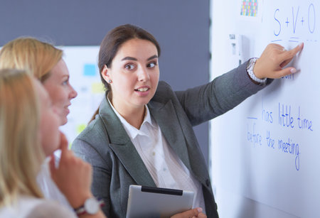 Business, education and office concept - business team with flip board in office discussing something.の写真素材