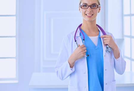 Young doctor woman standing near table, isolated on white backgroundの写真素材