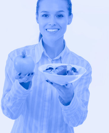 Portrait of a beautiful woman doctor holding a plate with fresh vegetables and green apple. Woman doctorの写真素材