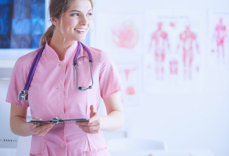 Smiling female doctor with a folder in uniform standing at hospitalの写真素材