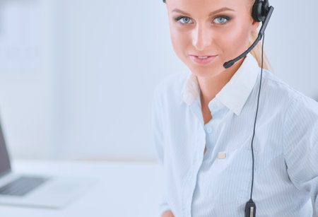 Portrait of smiling receptionist using laptop computer and headset at office deskの写真素材