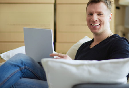 Portrait of happy young man moving in new home. Man holding digital tablet in his armsの写真素材