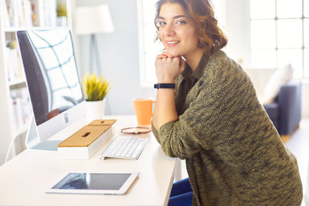 Happy woman working using multiple devices on a desk at homeの写真素材