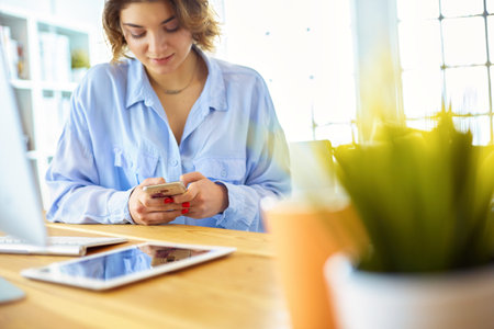 Happy woman working using multiple devices on a desk at homeの写真素材