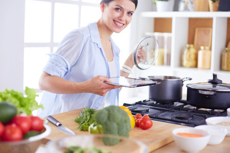 Young woman standing by the stove in the kitchenの写真素材