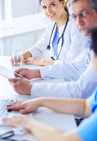 Smiling doctor using a laptop working with her colleagues in a bright hospital roomの写真素材