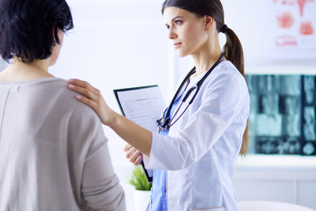 Medical consultation. Female doctor holding a patient by her shoulder, soothing her fearの写真素材