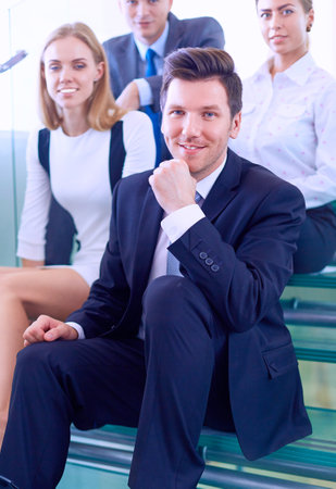 Business people sitting on the ladder in officeの写真素材