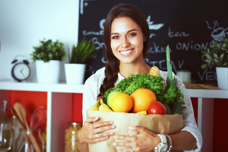 Young woman holding grocery shopping bag with vegetablesの写真素材