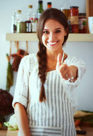 Young woman standing near desk in the kitchenの写真素材