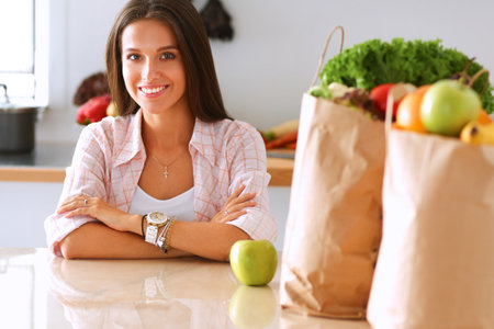 Young woman sitting near desk in the kitchenの写真素材