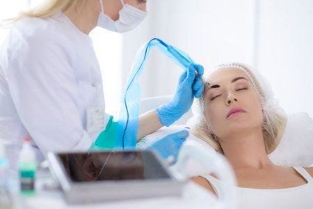 Permanent makeup for eyebrows. Closeup of beautiful woman with thick brows in beauty salonの写真素材