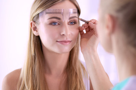Permanent makeup for eyebrows. Closeup of beautiful woman with thick brows in beauty salonの写真素材
