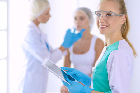 Beautiful woman face near doctor with syringeの写真素材