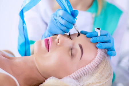 Permanent makeup for eyebrows. Closeup of beautiful woman with thick brows in beauty salonの写真素材
