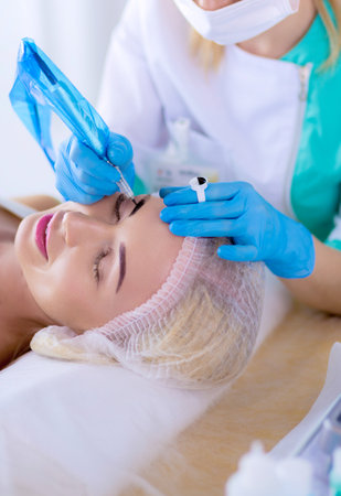 Permanent makeup for eyebrows. Closeup of beautiful woman with thick brows in beauty salonの写真素材