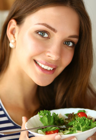Young woman eating salad and holding a mixed saladの写真素材