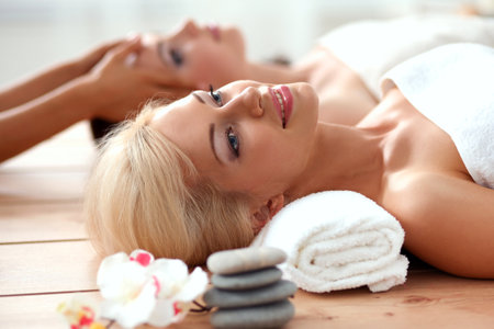 Two young beautiful women relaxing and enjoying at the spa centerの写真素材
