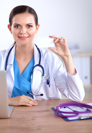 Beautiful young smiling female doctor sitting at the desk and writing.の写真素材