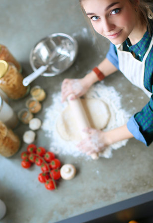 Young woman with orange juice and tablet in kitchenの写真素材