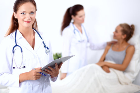 Smiling female doctor with a folder in uniform standing at hospitalの写真素材