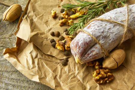 Italian salami wih sea salt, rosemary, garlic and nuts on paper. Rustic style. Top view.の写真素材
