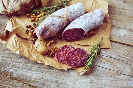Italian salami wih sea salt, rosemary, garlic and nuts on paper. Rustic style. Close up.の写真素材