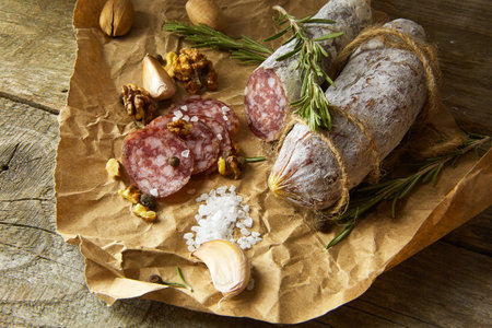Italian salami wih sea salt, rosemary, garlic and nuts on paper. Rustic style. Top view.の写真素材