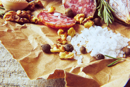 Italian salami wih sea salt, rosemary, garlic and nuts on paper. Rustic style. Top view.の写真素材