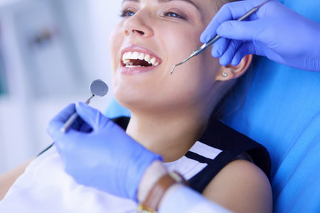 Young Female patient with open mouth examining dental inspection at dentist office.の写真素材