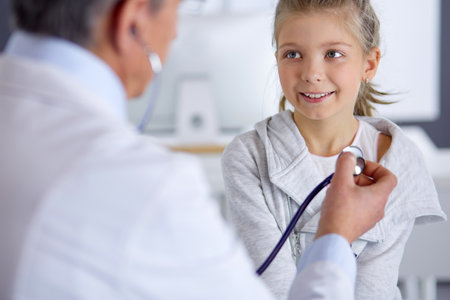 Girl and doctor with stethoscope listening to heartbeatの写真素材