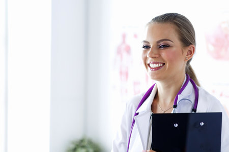 Smiling female doctor with a folder in uniform standingの写真素材